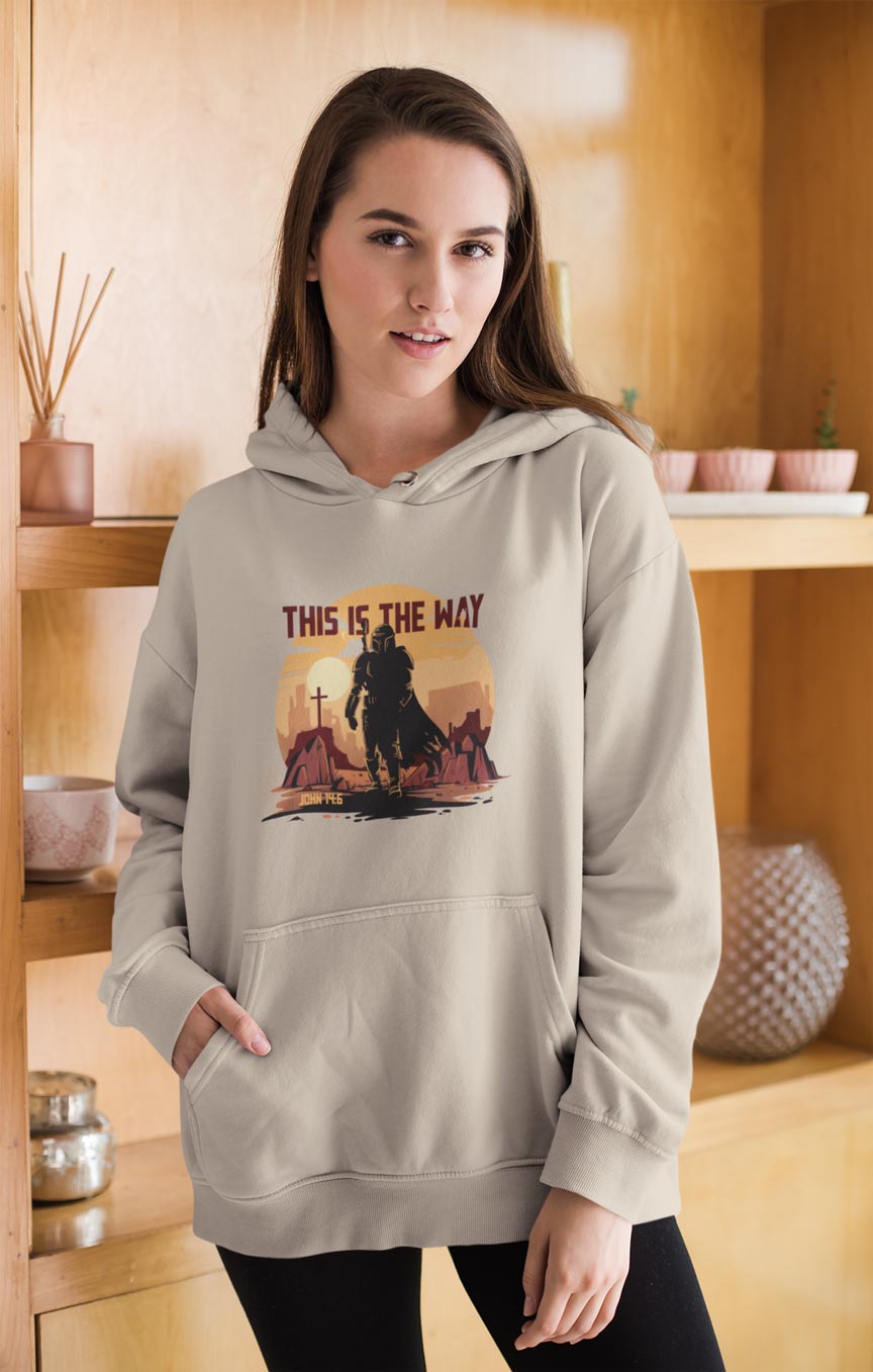 Person wearing a hoodie with a graphic design and text in a room with wooden shelves.