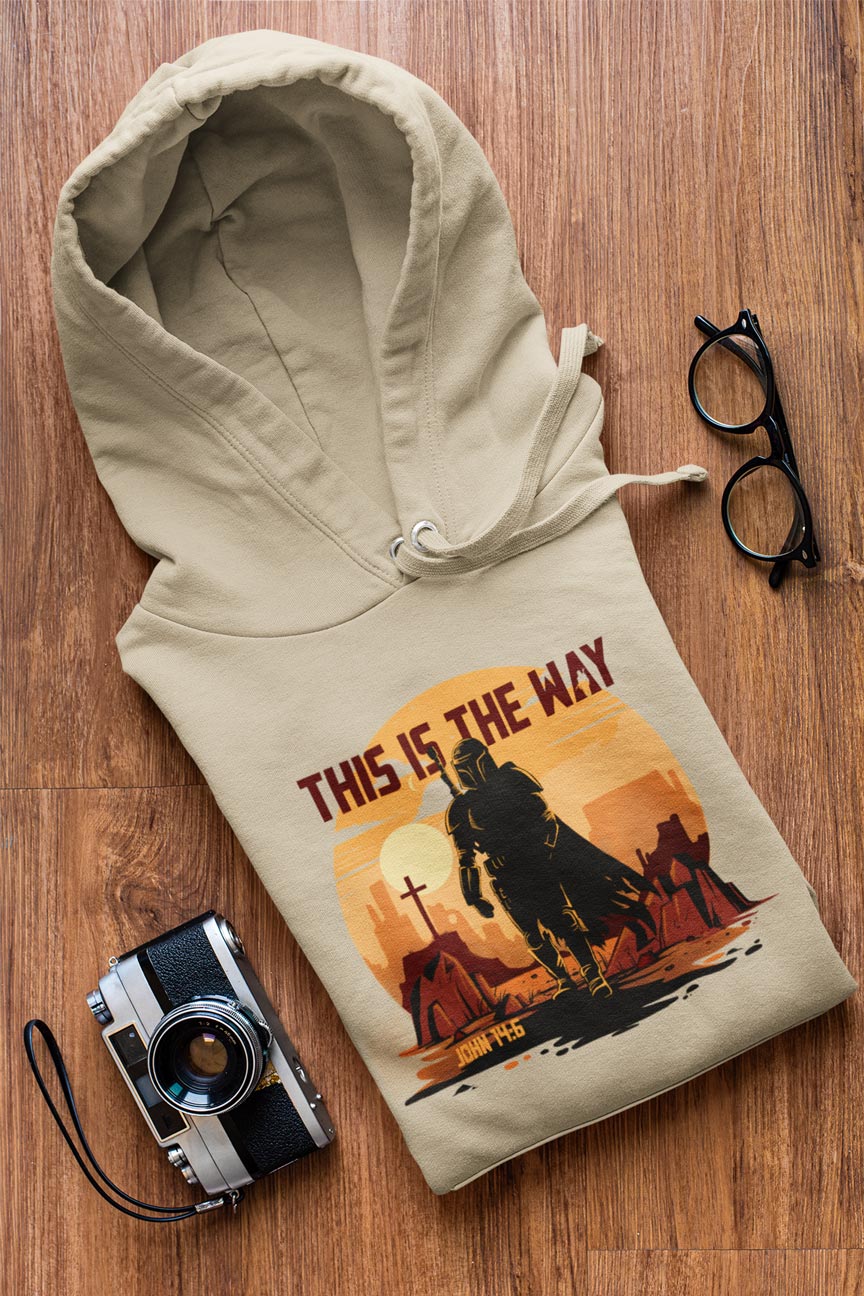 Beige hoodie with a graphic design on a wooden surface with a camera and glasses.