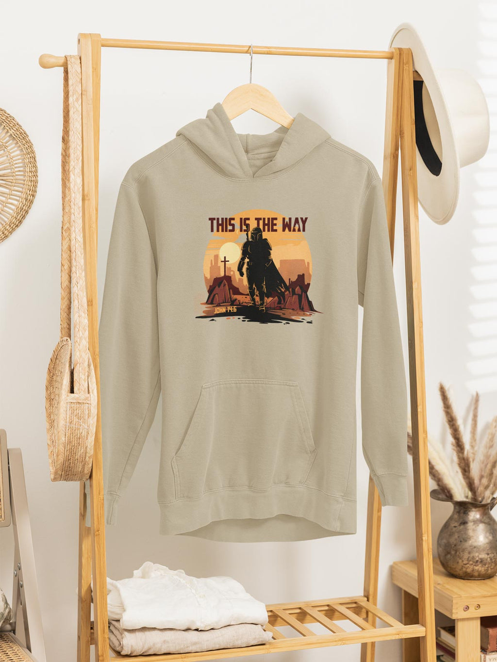 Beige hoodie with 'This is the Way' graphic on a wooden rack.